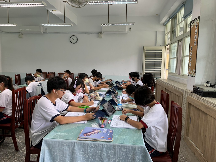 學生們戴著耳機,一邊觀看影片、一邊書寫講義。(圖片1)